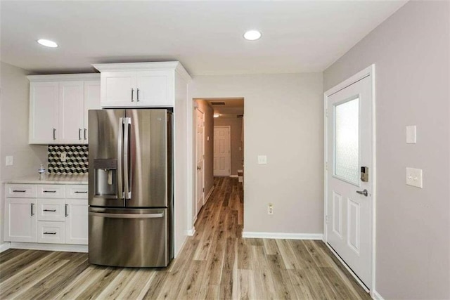 kitchen featuring light hardwood / wood-style floors, stainless steel fridge, white cabinetry, and decorative backsplash