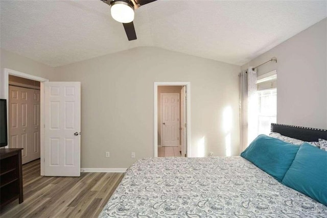 bedroom with hardwood / wood-style floors, ceiling fan, a textured ceiling, and lofted ceiling