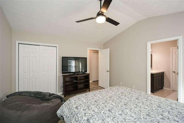 bedroom featuring light hardwood / wood-style floors, ensuite bathroom, ceiling fan, lofted ceiling, and a closet