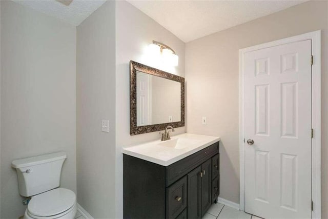 bathroom featuring toilet, vanity, a textured ceiling, and tile patterned floors