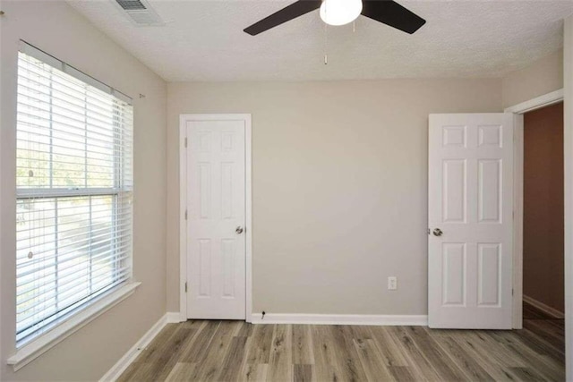 unfurnished bedroom featuring ceiling fan, a textured ceiling, and light hardwood / wood-style flooring