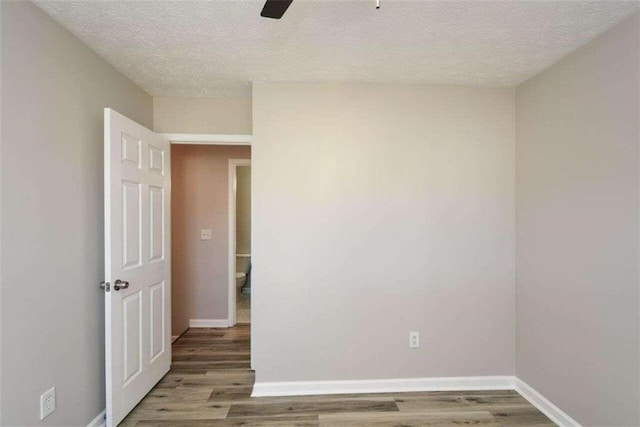 empty room with hardwood / wood-style floors, ceiling fan, and a textured ceiling