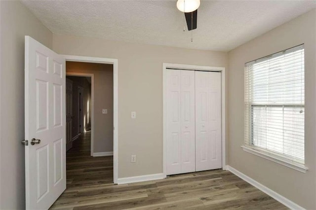 unfurnished bedroom with dark wood-type flooring, a closet, a textured ceiling, and ceiling fan