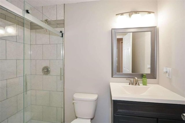 bathroom featuring toilet, vanity, and a shower with shower door