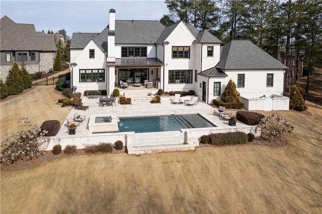 rear view of property with an outdoor fire pit, a pool with hot tub, a patio area, and a lawn