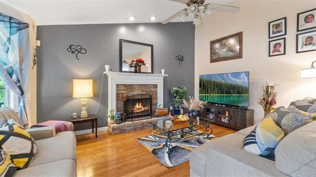 living area with a ceiling fan, a stone fireplace, wood finished floors, baseboards, and recessed lighting