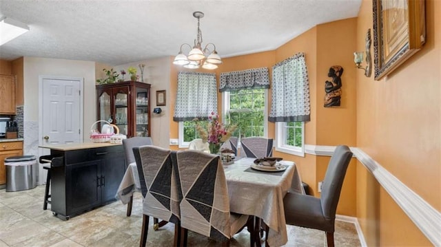 dining area with a textured ceiling, a chandelier, and baseboards