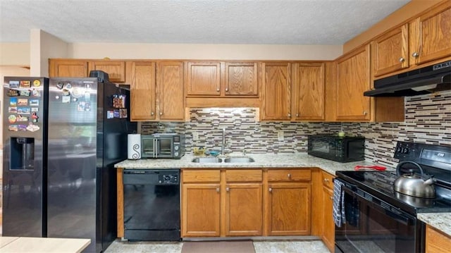 kitchen with a sink, a textured ceiling, decorative backsplash, under cabinet range hood, and black appliances