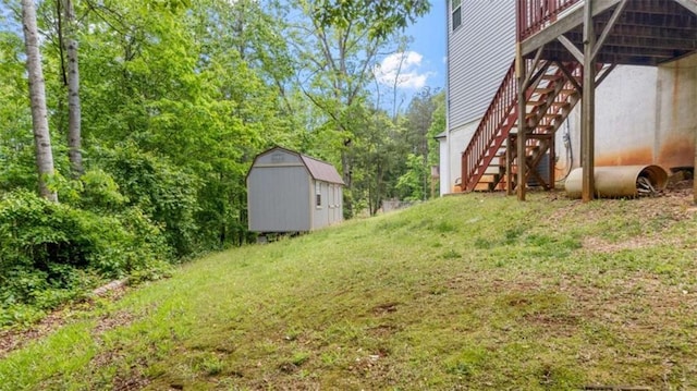 view of yard with a deck, an outbuilding, stairs, and a shed