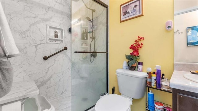 bathroom featuring toilet, a marble finish shower, and vanity