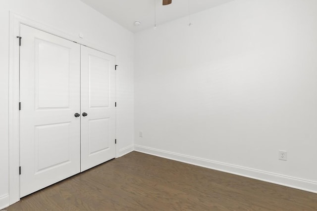 unfurnished bedroom with dark wood-type flooring, ceiling fan, and a closet