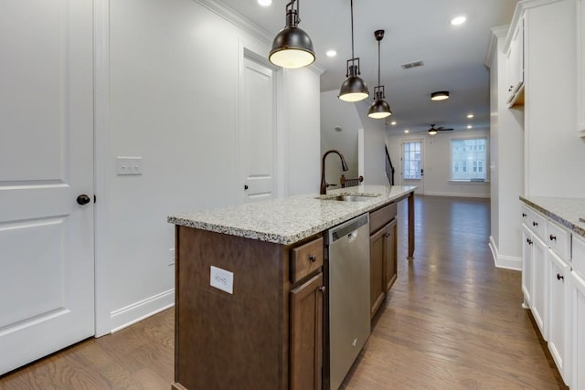 kitchen featuring sink, white cabinetry, hanging light fixtures, dishwasher, and light stone countertops