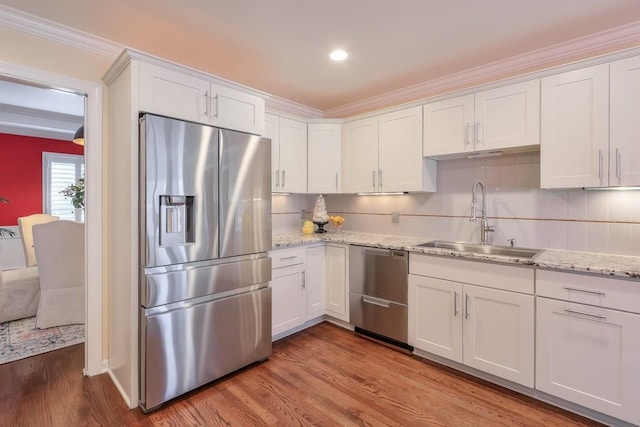 kitchen with appliances with stainless steel finishes, dark wood-type flooring, a sink, and white cabinets