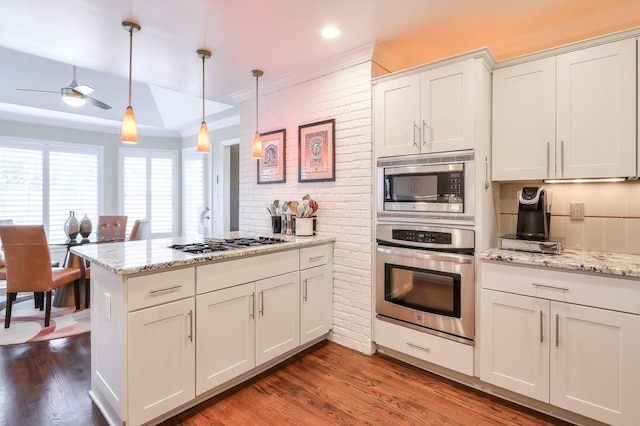 kitchen with stainless steel appliances, brick wall, a peninsula, dark wood-style floors, and a raised ceiling