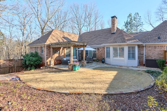 back of house with brick siding, a patio, a chimney, and a pergola