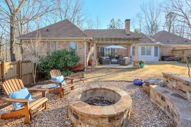 rear view of house featuring an outdoor living space with a fire pit, brick siding, a chimney, a patio, and fence