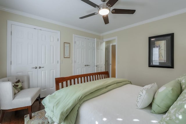 bedroom with ceiling fan, ornamental molding, two closets, and wood finished floors