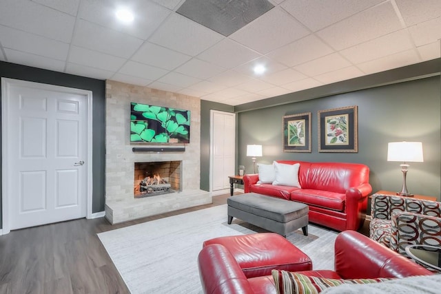 living room featuring baseboards, visible vents, wood finished floors, a paneled ceiling, and a fireplace