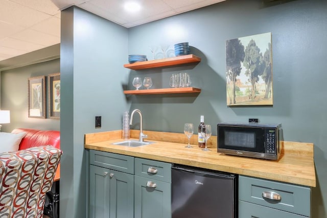 bar with dishwashing machine, a drop ceiling, a sink, and wet bar