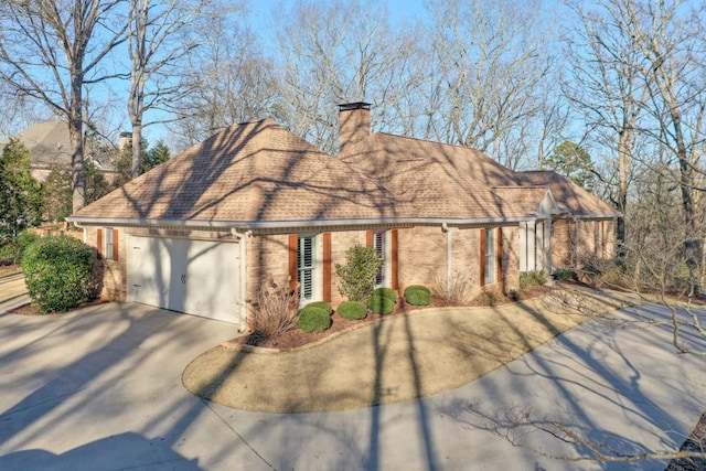 view of front facade with brick siding, roof with shingles, a chimney, an attached garage, and driveway