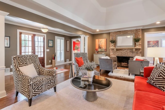 living area with visible vents, wood finished floors, crown molding, ornate columns, and a fireplace