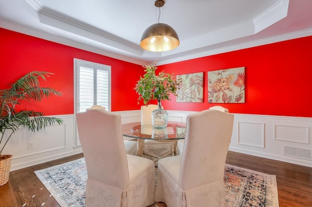 dining space featuring a wainscoted wall, a raised ceiling, and wood finished floors