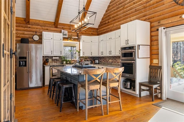 kitchen with appliances with stainless steel finishes, a kitchen island, pendant lighting, white cabinetry, and a breakfast bar area