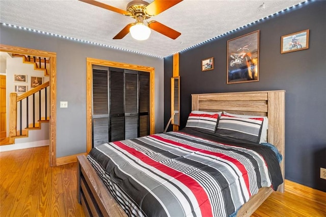 bedroom with ceiling fan, wood-type flooring, a textured ceiling, and a closet