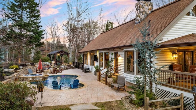 pool at dusk with a gazebo, an in ground hot tub, and a patio