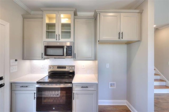 kitchen with crown molding, appliances with stainless steel finishes, hardwood / wood-style floors, and backsplash