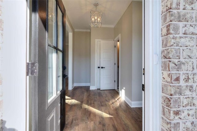 corridor with crown molding, dark wood-type flooring, and a chandelier