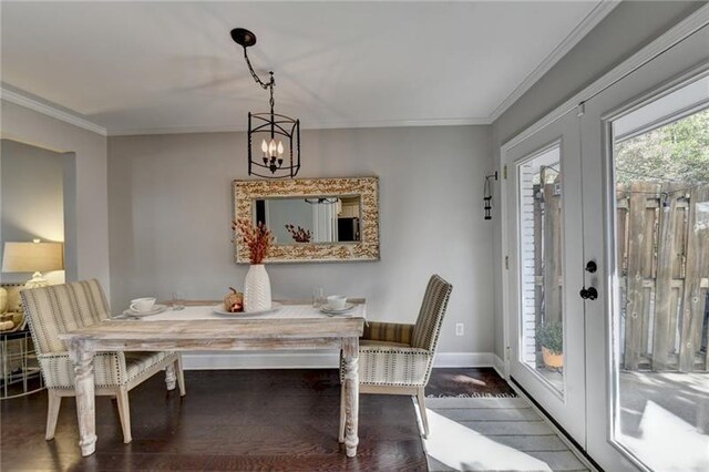 dining room featuring baseboards, wood finished floors, a chandelier, and ornamental molding