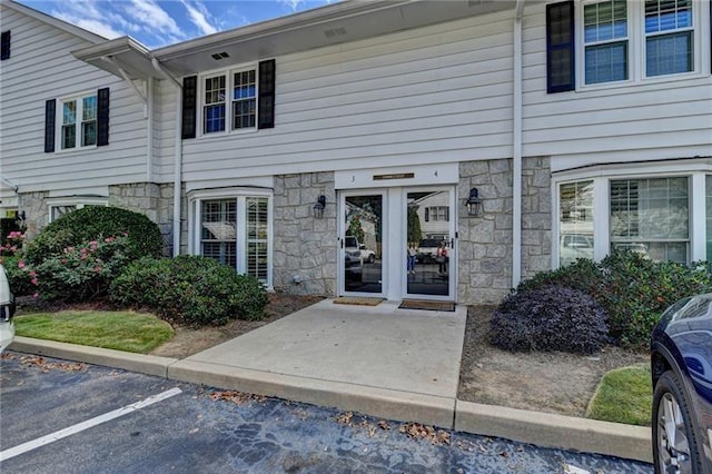 view of exterior entry with stone siding and uncovered parking