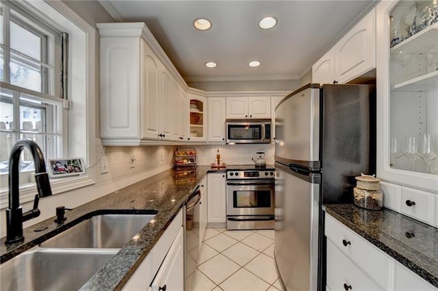 kitchen with light tile patterned floors, a sink, decorative backsplash, glass insert cabinets, and appliances with stainless steel finishes