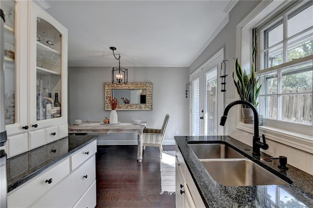 kitchen featuring dark wood-type flooring, ornamental molding, a sink, dark stone countertops, and white cabinets