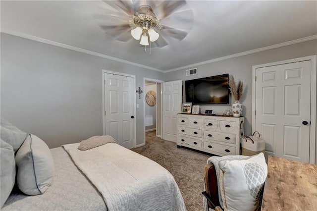 carpeted bedroom with visible vents, baseboards, ornamental molding, and a ceiling fan