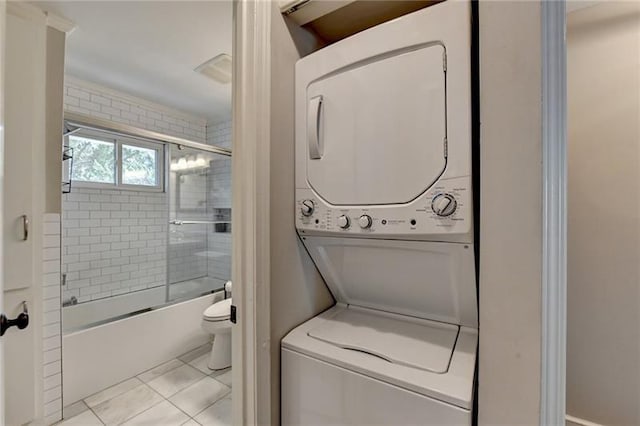 clothes washing area with tile patterned flooring, laundry area, and stacked washing maching and dryer