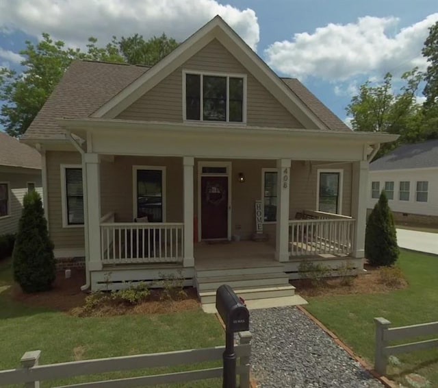 view of front facade with covered porch, a front lawn, and a shingled roof