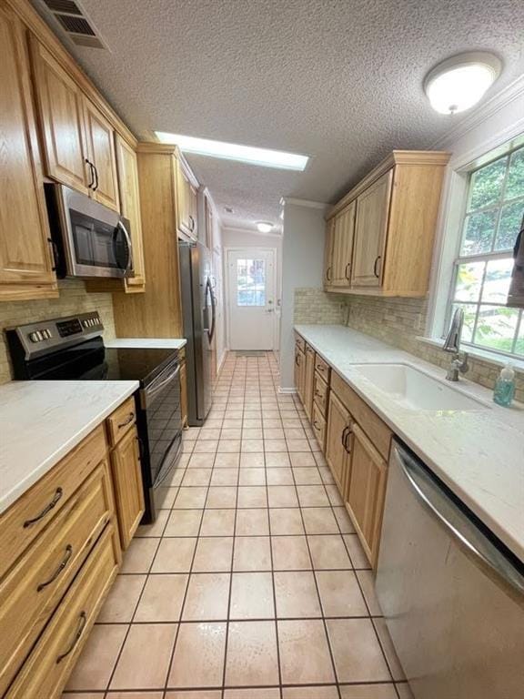 kitchen with sink, stainless steel appliances, light tile patterned floors, and plenty of natural light