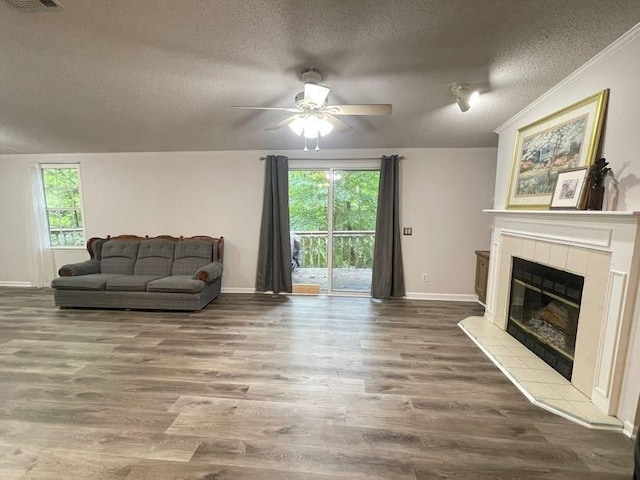 living room with a tiled fireplace, a textured ceiling, plenty of natural light, and hardwood / wood-style floors