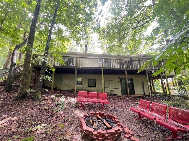 rear view of property featuring a deck and a fire pit