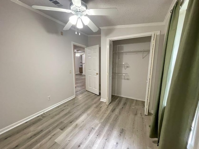 unfurnished bedroom with ornamental molding, light wood-type flooring, a closet, and ceiling fan