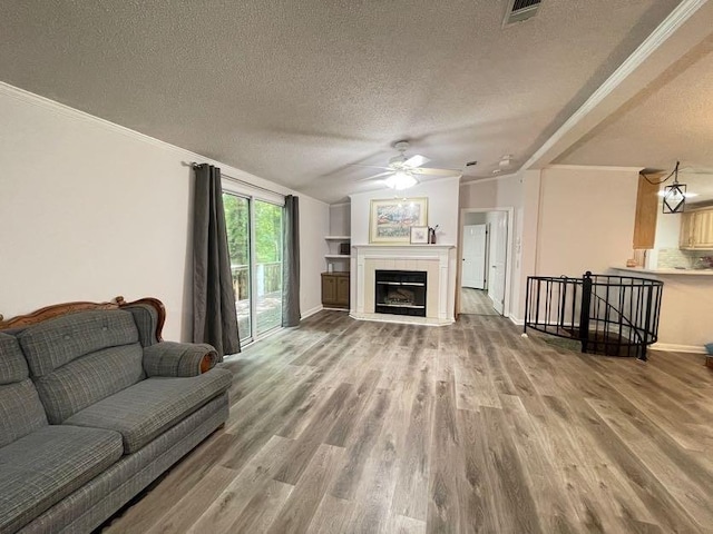 living room featuring ceiling fan, a textured ceiling, wood-type flooring, vaulted ceiling, and ornamental molding