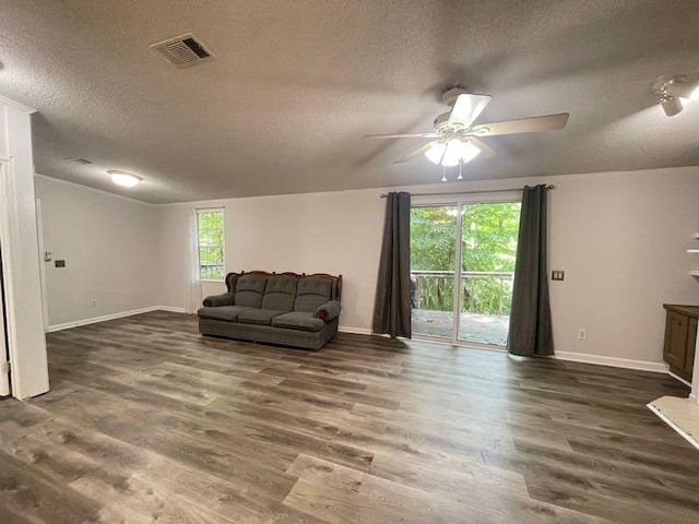 living room featuring dark wood-type flooring, a textured ceiling, and plenty of natural light