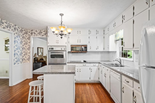 kitchen with dark wood-type flooring, sink, black appliances, white cabinets, and a center island