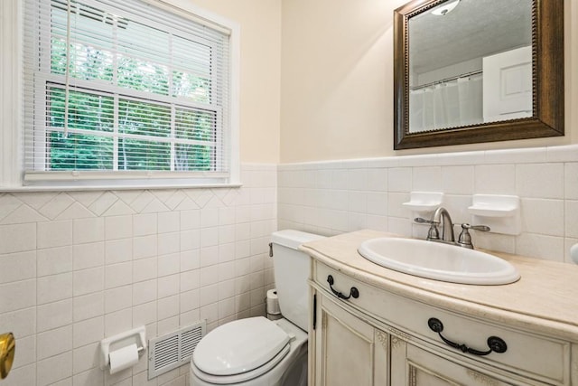 bathroom with vanity, toilet, and tile walls