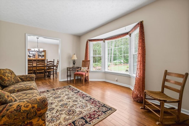 living area featuring hardwood / wood-style floors, a chandelier, and a textured ceiling