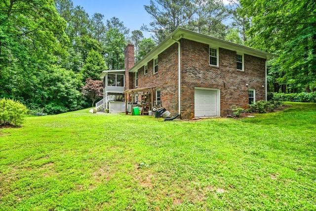 back of house featuring a sunroom, a garage, and a yard