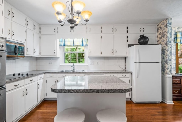 kitchen featuring dark wood-type flooring, sink, white refrigerator, a center island, and white cabinetry