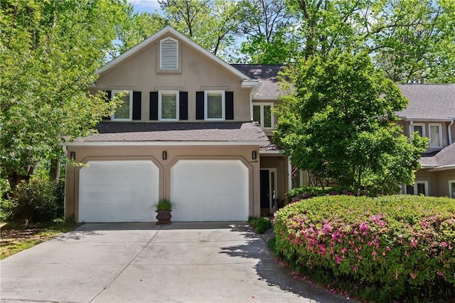 view of front of home featuring a garage, a shingled roof, concrete driveway, and stucco siding